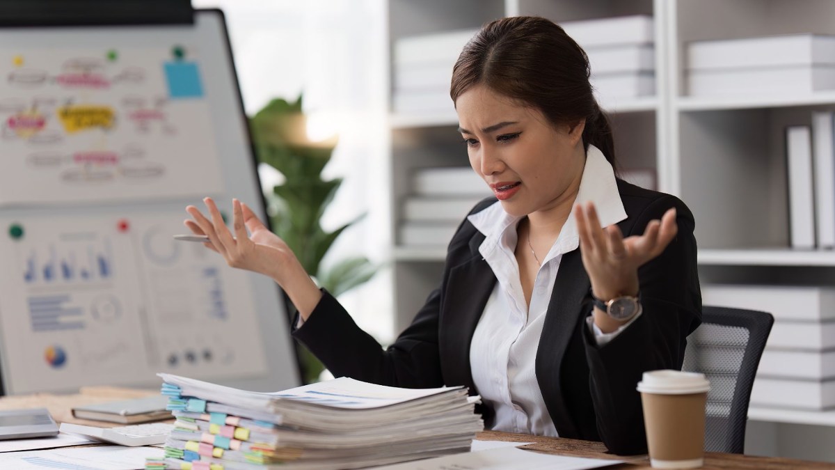 Une manager face à une pile de dossiers, complètement dépassée.