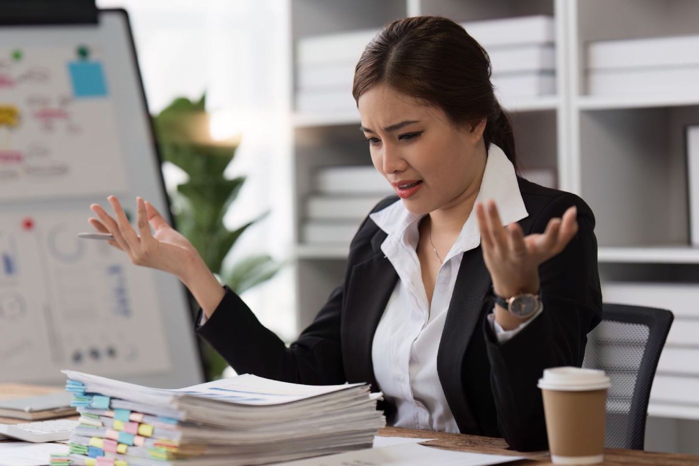 Une manager face à une pile de dossiers, complètement dépassée.